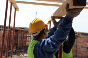 A construction inspector reviewing house framing and building plans at a residential jobsite.